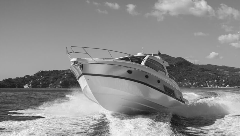 A speedboat cuts through water near a scenic coastline.